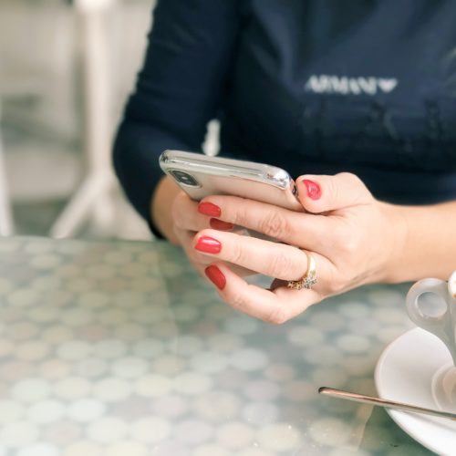 Close-up hands using smartphone over coffee
