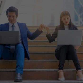 Two coworkers on steps using laptops