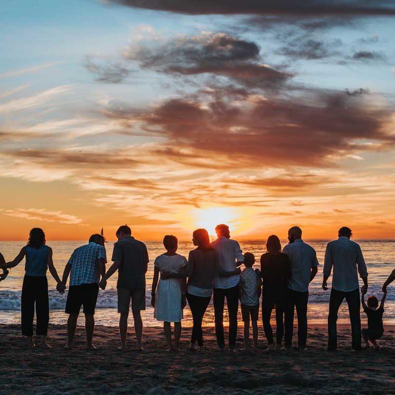 Friends standing on beach at sunset
