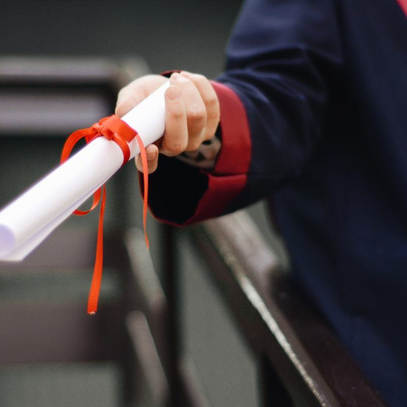 person holding white paper with red ribbon