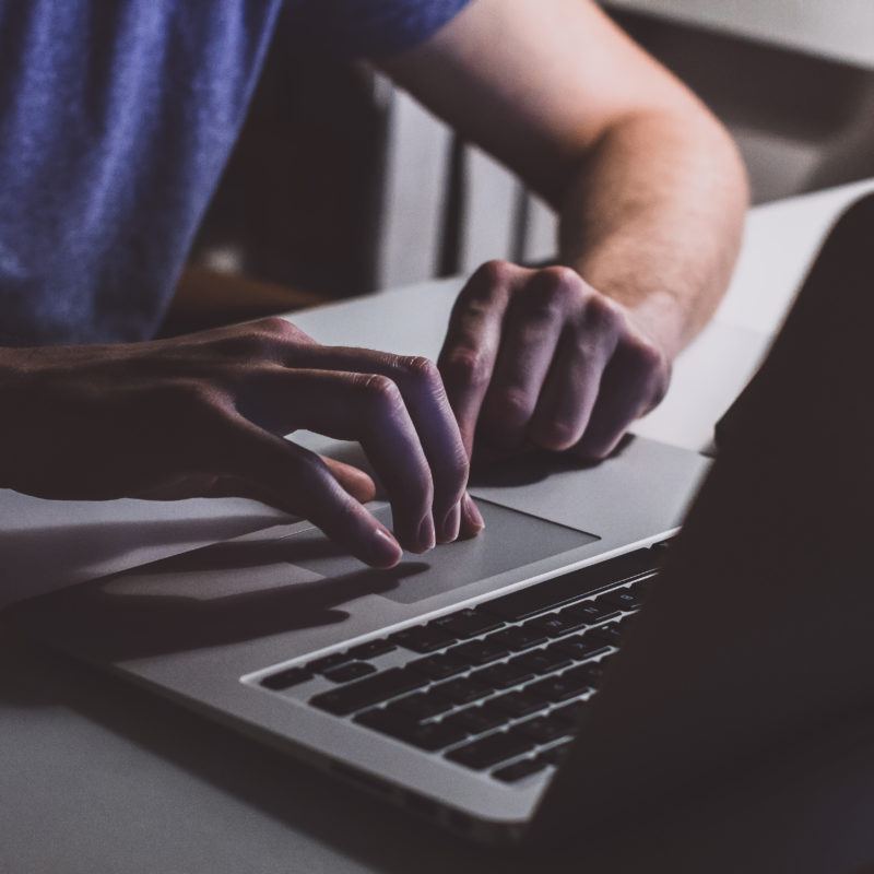 person touching open macbook on table