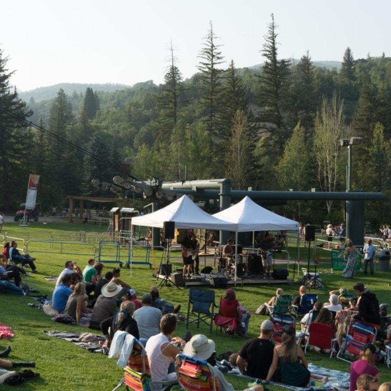 Outdoor community event with tents and seated crowd