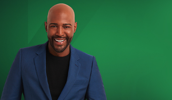Smiling man in a blue jacket with green backdrop (professional headshot).