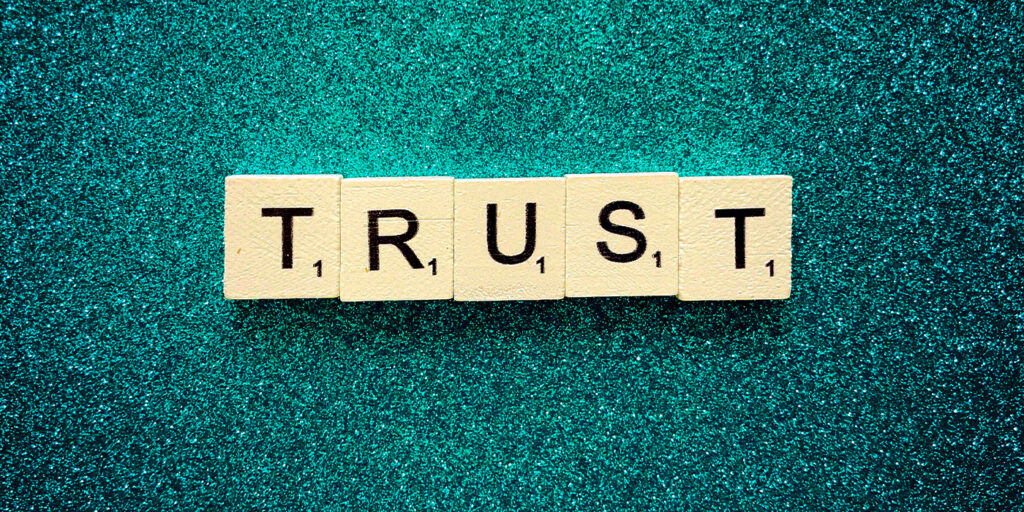 Scrabble tiles spelling TRUST on teal