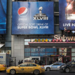 Times Square scene with huge Pepsi Super Bowl ads and yellow taxis in front of a Subway entrance
